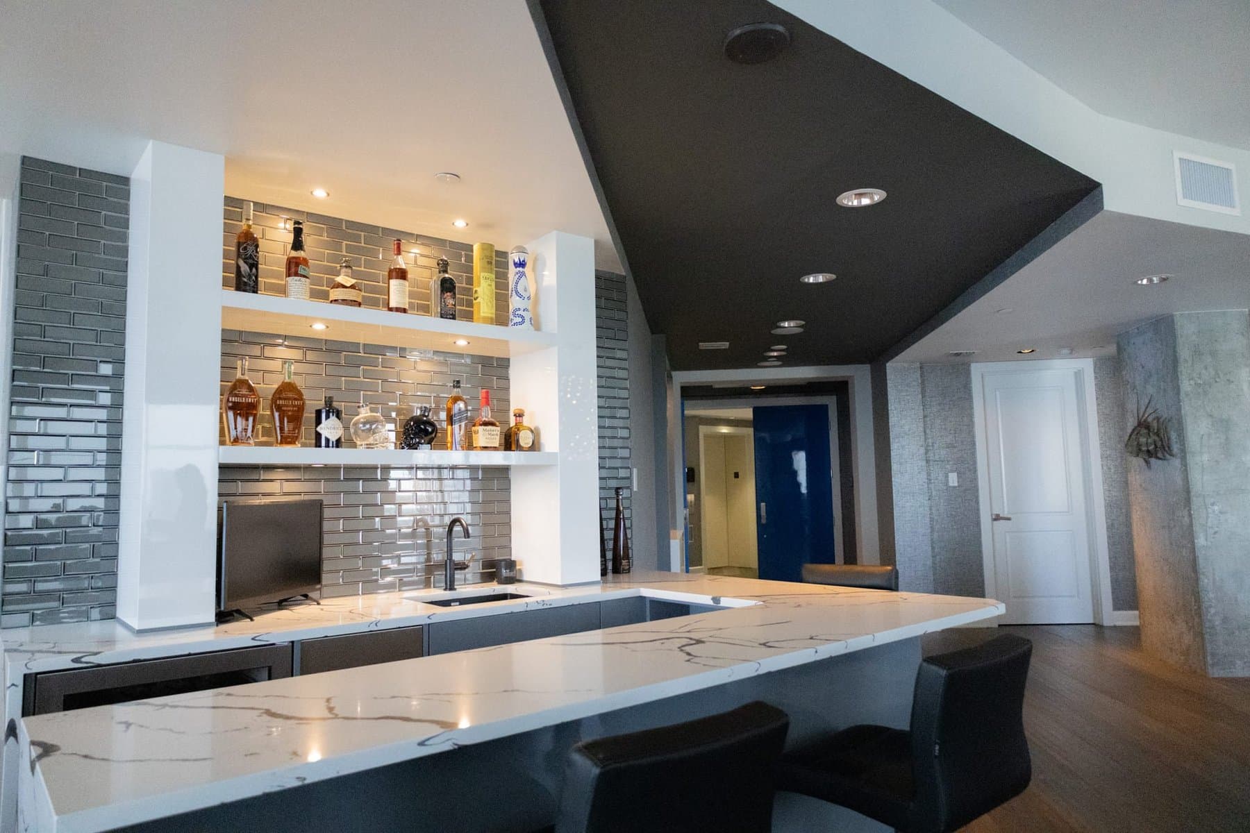 Custom wet bar with quartz countertop and subway tile backsplash in a high-rise condo remodel