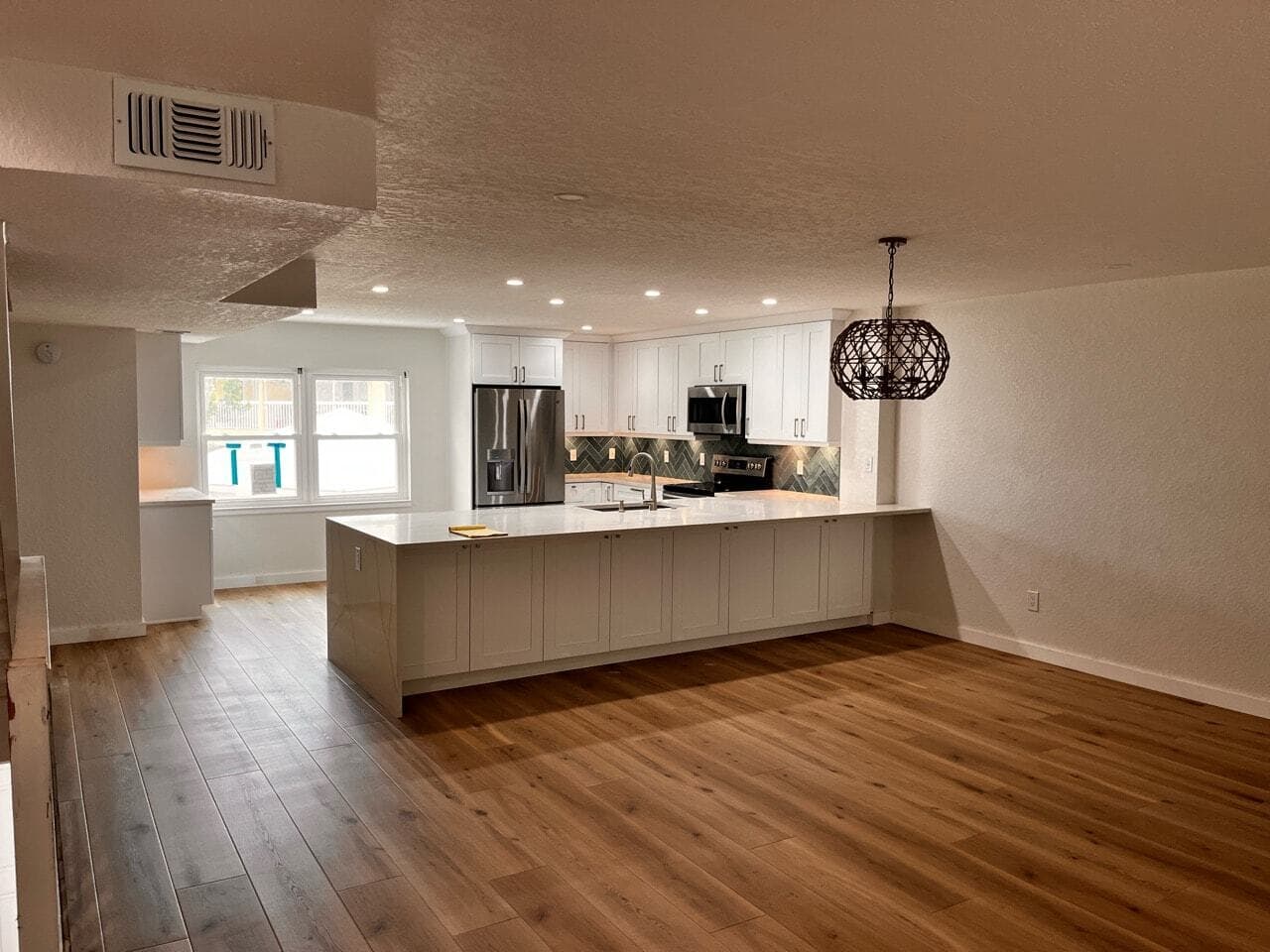 Open-concept kitchen remodel with island and herringbone backsplash in Pinellas County