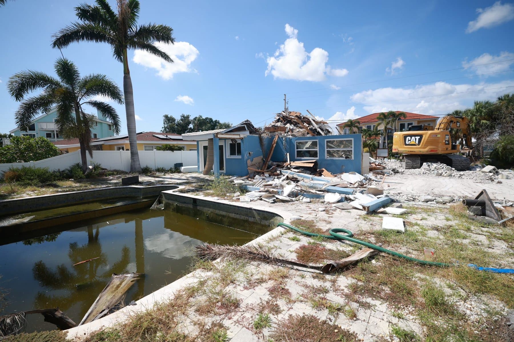 Home demolition in progress with excavator clearing a lot for new construction in St. Petersburg