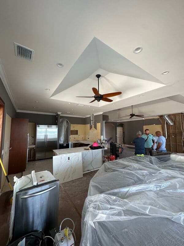 Revolution Contractors crew installing kitchen tray ceiling, quartz island, and cabinetry in a waterfront remodel