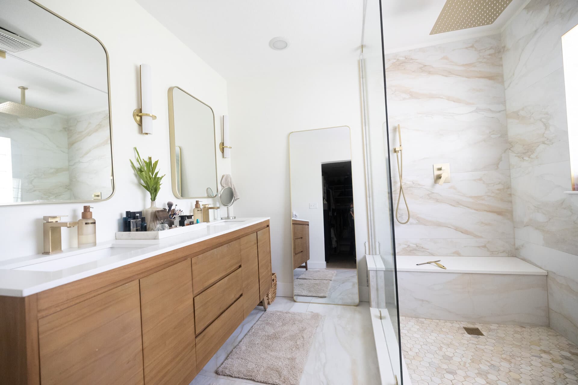 Marble wall shower with floating vanity and gold fixtures