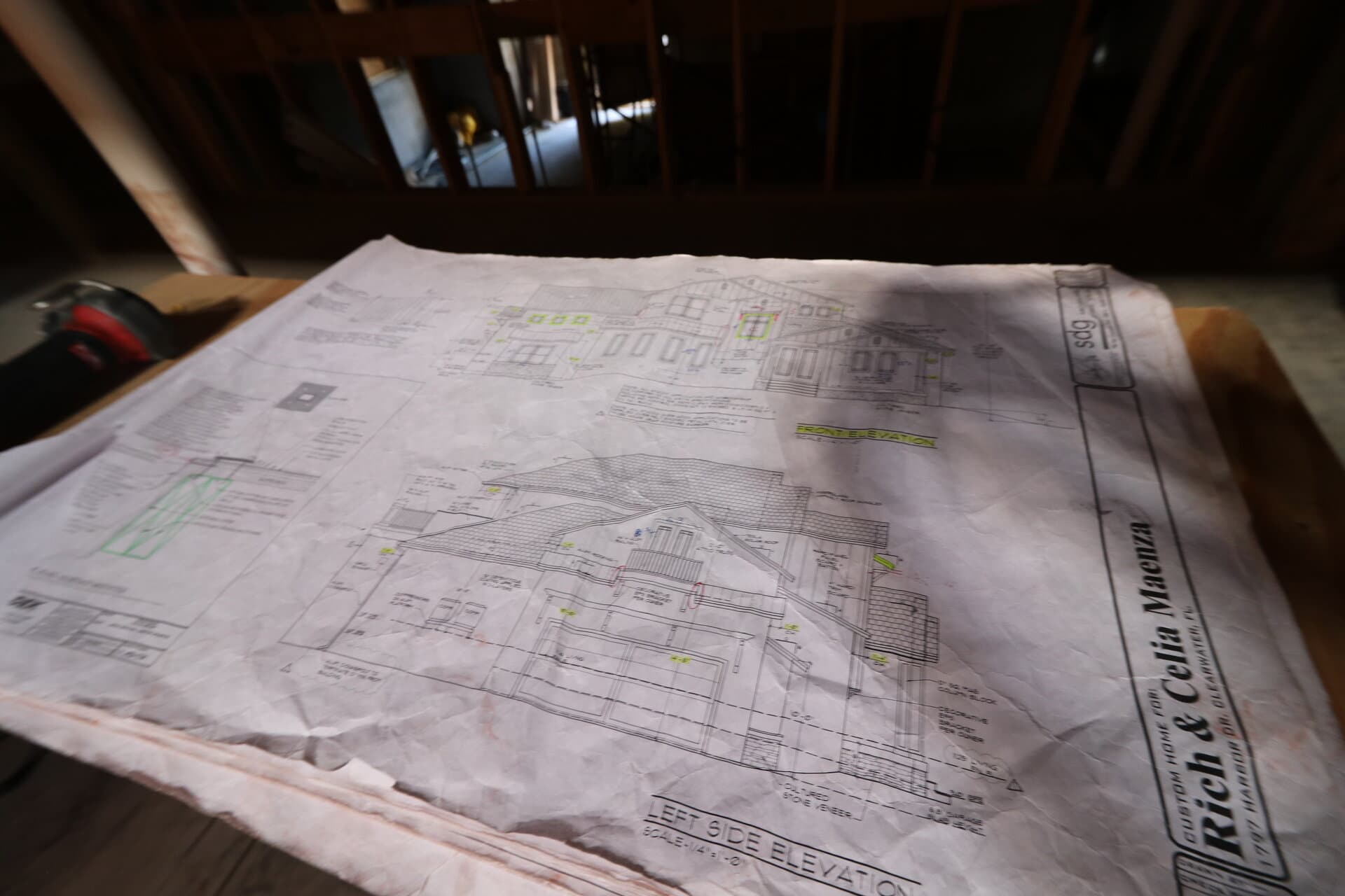 Real blueprints spread out on workbench with framing visible behind