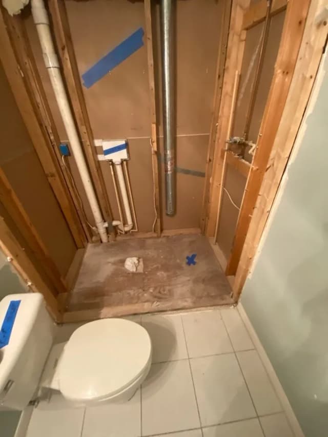 Bathroom demolition phase showing framing exposed and debris cleared